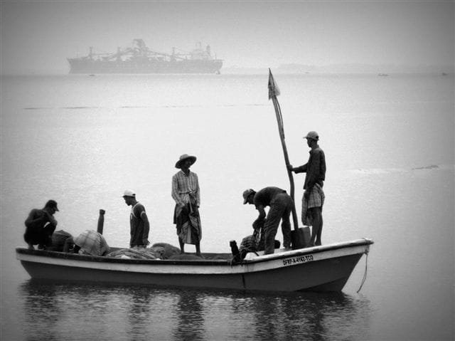 Image of multiple men on a boat in grayscale style.